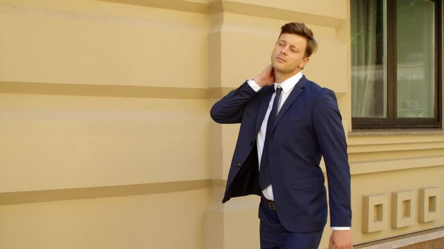 Closeup executive man walking alone at street. Guy flexing neck at sidewalk