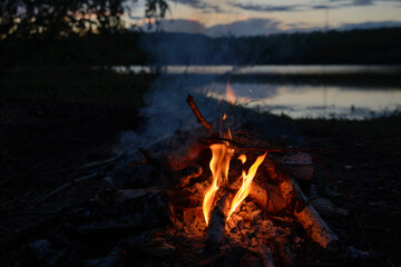 bonfire near the village lake against the background of sunset