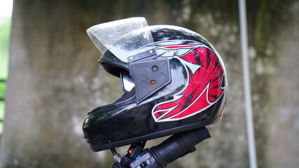 A colorful helmet mounted on a motorcycle handle. Old helmet with blurred background.