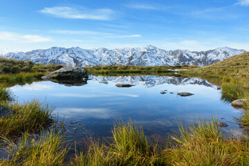 Bergsee mit schneebedeckten Alpen im Hintergrund