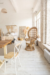 Large spacious room with a trendy loft design of sitting area. huge windows and stylish wicker light furniture inside. an abundance of ethnic decor
