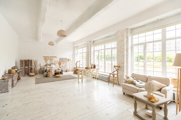 Large spacious room with a trendy loft design of sitting area. huge windows and stylish wicker light furniture inside. an abundance of ethnic decor