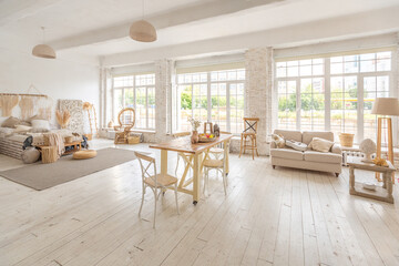 Large spacious room with a trendy loft design of sitting area. huge windows and stylish wicker light furniture inside. an abundance of ethnic decor