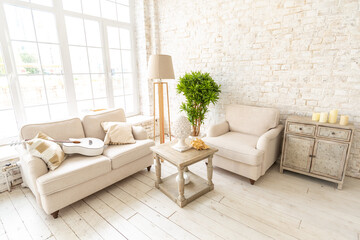 Large spacious room with a trendy loft design of sitting area. huge windows and stylish wicker light furniture inside. an abundance of ethnic decor