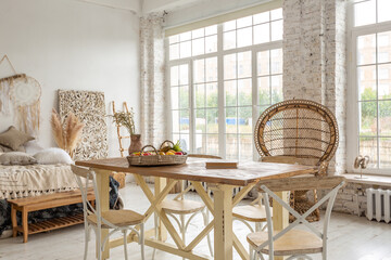 Large spacious room with a trendy loft design of sitting area. huge windows and stylish wicker light furniture inside. an abundance of ethnic decor