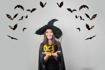 young woman in witch halloween costume with hat standing and smiling over white background
