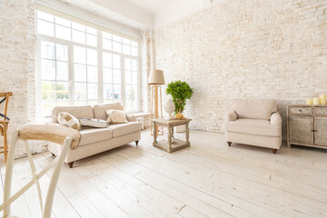 Large spacious room with a trendy loft design of sitting area. huge windows and stylish wicker light furniture inside. an abundance of ethnic decor