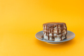 Chocolate cake with streams on a plate. Halloween concept, trick or treat. Handmade cooking, sweets with flows down. Orange background, copy space for text. Selective focus, blur.