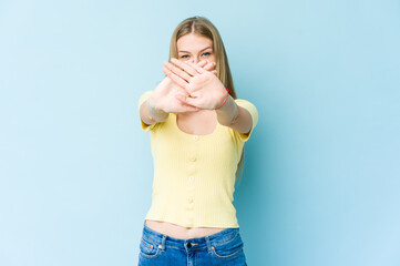 Young blonde woman isolated on blue background doing a denial gesture