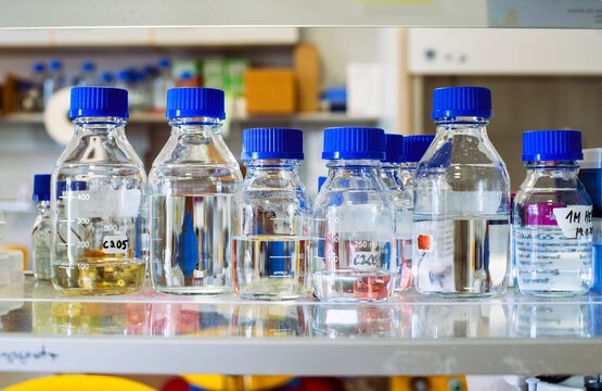 Stock solutions for biochemistry experiments, bottles with blue cap are on a shelf, blurry background