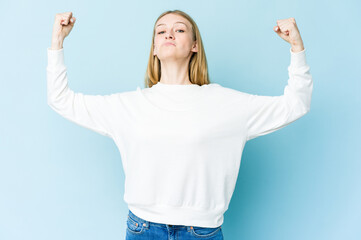 Fototapeta na wymiar Young blonde woman isolated on blue background showing strength gesture with arms, symbol of feminine power