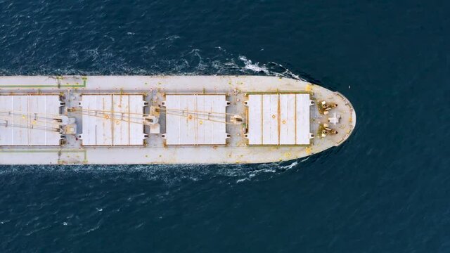Cargo ship sailing on the ocean to the sea port. A bulk carrier or bulker - a merchant ship specially designed to transport unpackaged bulk cargo - grains, ore, coal or timber. Aerial top down view