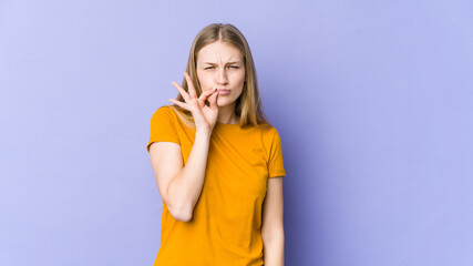 Young blonde woman isolated on purple background with fingers on lips keeping a secret.