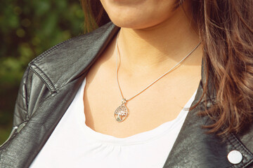 Female neckline wearing tiny silver chain with silver pendant in the shape of tree in mandala