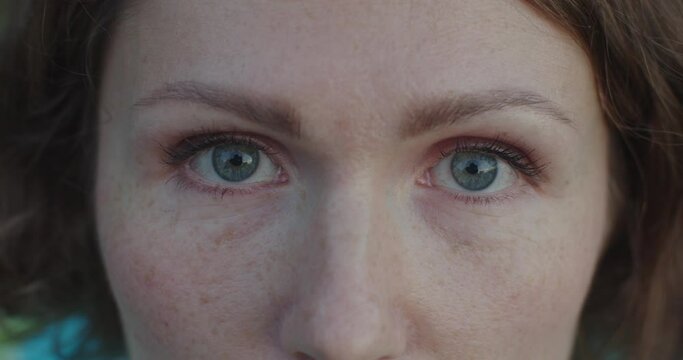 Extra close up female blue eyes with little make-up mascara opening slow motion detailed crop. Macro portrait of white woman with freckles looking seriously. Skin care healthy eyes eyesight concept