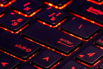 Black keyboard keys with red backlight. Selected focus on enter key