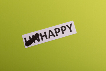 card wit text unhappy, cutting word 'un' so it written 'happy'. Copy space. Lime background. Studio shoot
