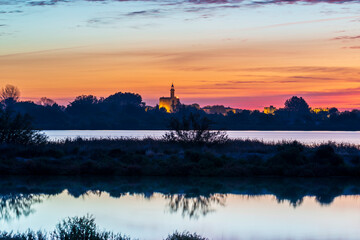 Naklejka premium The Constance tower of the fortifications of the medieval city of Aigues-Mortes from the Marette pond at sunrise, in the Gard, in Occitania, France