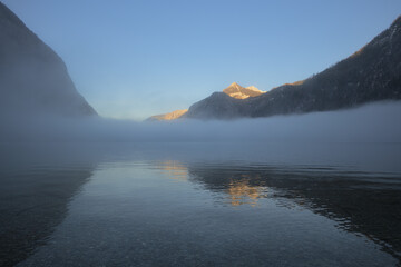 Eine Nebeldecke über dem Königssee in der Abenddämmerung