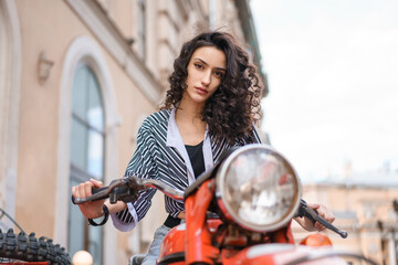 Fototapeta na wymiar Beautiful young woman sitting on a motorcycle on a city street