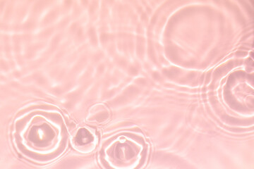 de-focused. Closeup of pink transparent clear calm water surface texture with splashes and bubbles. Trendy abstract summer nature background. Coral colored waves in sunlight.