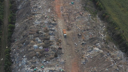 Flying over industrial truck dumping trash at open places at nature. Aerial shot of big rubbish pile lying among field in countryside. Global environmental pollution problem. Top view Slow motion