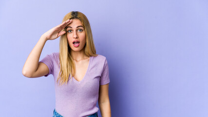 Young blonde caucasian woman shouts loud, keeps eyes opened and hands tense.