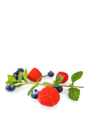 Strawberries and blueberries with mint leaves on a white background. Space for text