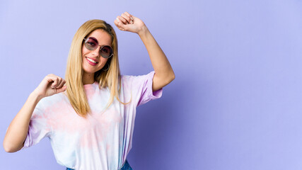 Naklejka premium Young blonde caucasian woman celebrating a special day, jumps and raise arms with energy.