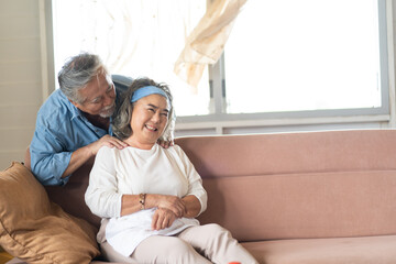 Asian Elderly couple at home. Old woman in pain lying on sofa with senior husband at home