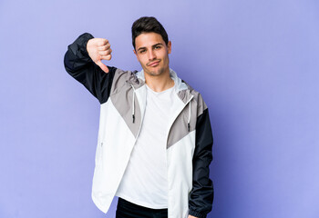 Young caucasian man isolated on purple background showing thumb down, disappointment concept.