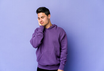 Young caucasian man isolated on purple background who is bored, fatigued and need a relax day.