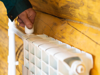 adjustment of the tap on the radiator. a man's hand turns the tap. heating of a private wooden...