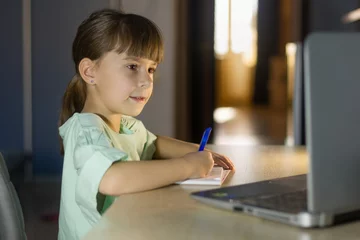 Deurstickers Online onderwijs op afstand. Klein schoolmeisje studeert thuis. © Albert Ziganshin
