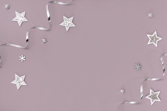 Flat composition of Christmas decorations in silver on a pink background.