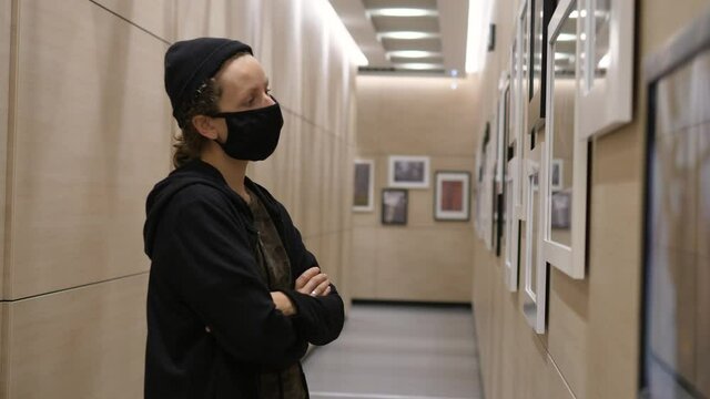 Photography exhibition. Person wearing protective face mask contemplating art of photography