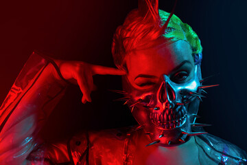 Portrait of suicidal cyberpunk woman with mohawk hairstyle in spiked skull mask with finger on her forehead.