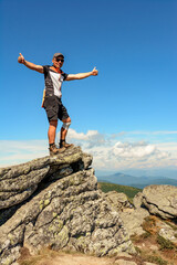 A man stands on the edge of a stone on one of the peaks of the Ukrainian Carpathians, the Montenegrin ridge, picturesque mountains on the trampled trails of the Carpathians.