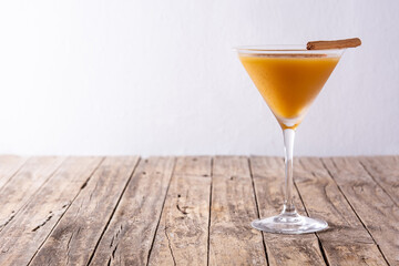 Pumpkin cocktail in glass on wooden table.Copy space