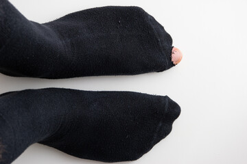 Caucasian male toe sticking out of worn out short nylon black plain socks with hole top view