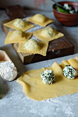 Fresh Raw Ravioli with Ricotta and Spinach on a blue background. Homemade raw uncooked italian pasta ravioli. Italian food.