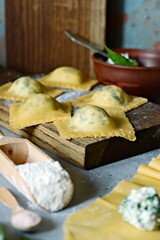 Fresh Raw Ravioli with Ricotta and Spinach on a blue background. Homemade raw uncooked italian pasta ravioli. Italian food.