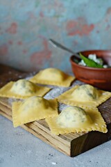 Fresh Raw Ravioli with Ricotta and Spinach on a blue background. Homemade raw uncooked italian pasta ravioli. Italian food.