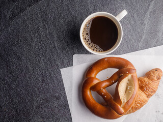 Homemade breads or bun, croissant  bakery ingredients and a cup of coffee on black slate background, breakfast food concept top view and copy space.top view