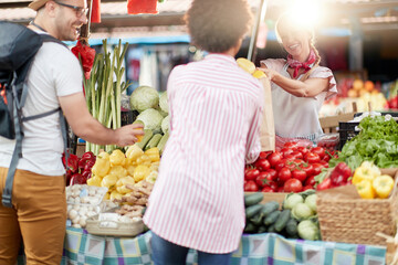 Seller woman offers fresh and organic vegetables at the green market or farmers market stall.  Young buyers choose and buy products for healthy food in grocery. All for diet healthy eating, lifestyle.