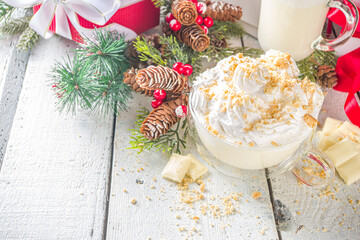 Obraz na płótnie Canvas Christmas winter hot chocolates idea, recipe. Cheesecake hot chocolate with cheesecake aroma and crumbs, white chocolate and creamy milk. On white wooden table background with Christmas decor