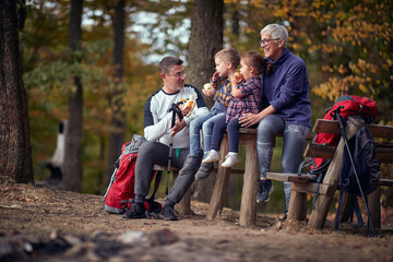 Grandmother, grandfather and grandchildren eating the fruits in the forest