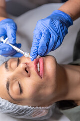 Beautiful, attractive, young woman, lying relaxed in dermatologist ordination, getting a rejuvenating lips treatment with hyaluronic acid filler. Cosmetics and beauty  corrections, skin care concept