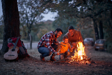 Father, son and grandson excited because of a campfire in the forest