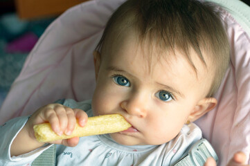 Precioso bebé en primer plano con ojos claros comiendo gusanitos